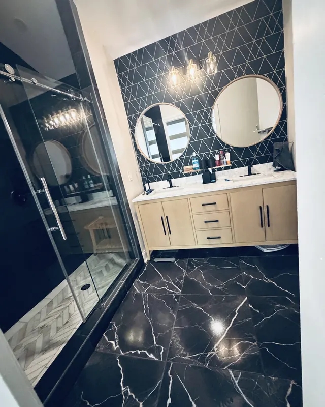 A bathroom with black marble floors, a glass shower and a double vanity, freshly cleaned