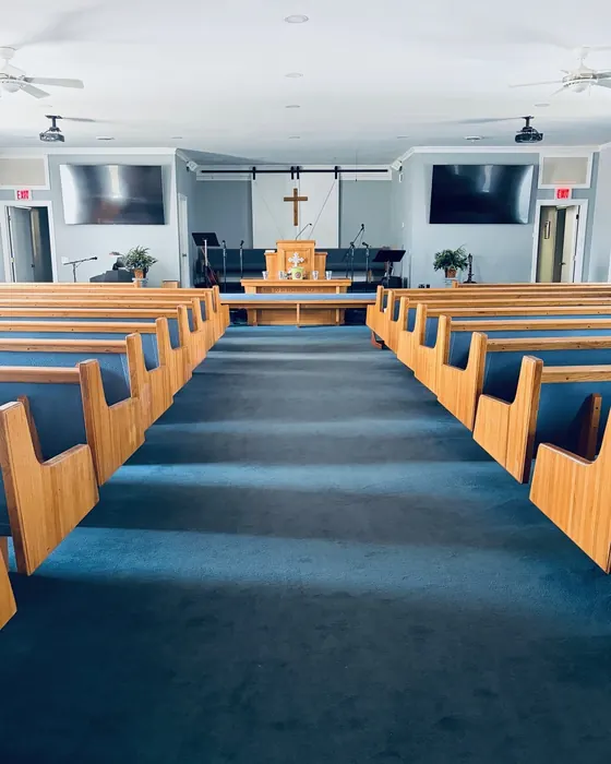 Church sanctuary with wooden pews and a vacuumed blue carpet aisle