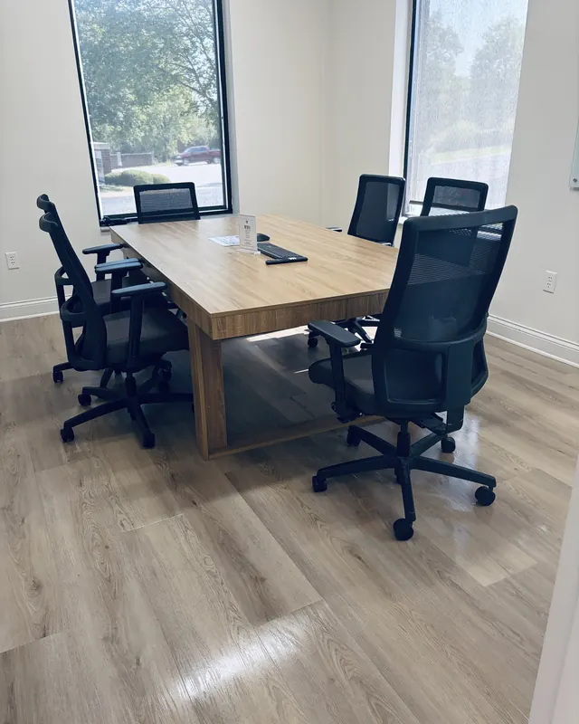 Office conference room with a wood table, mesh chairs and freshly cleaned floors