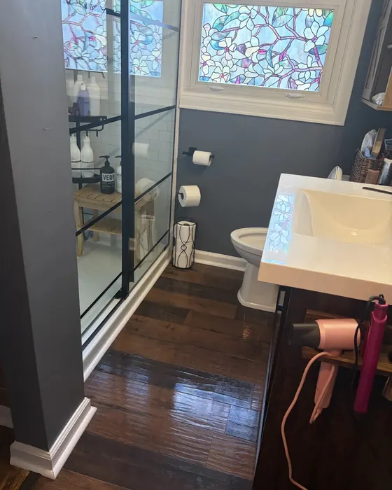 A reset bathroom with a clear vanity, clean shower glass and shining wood floors