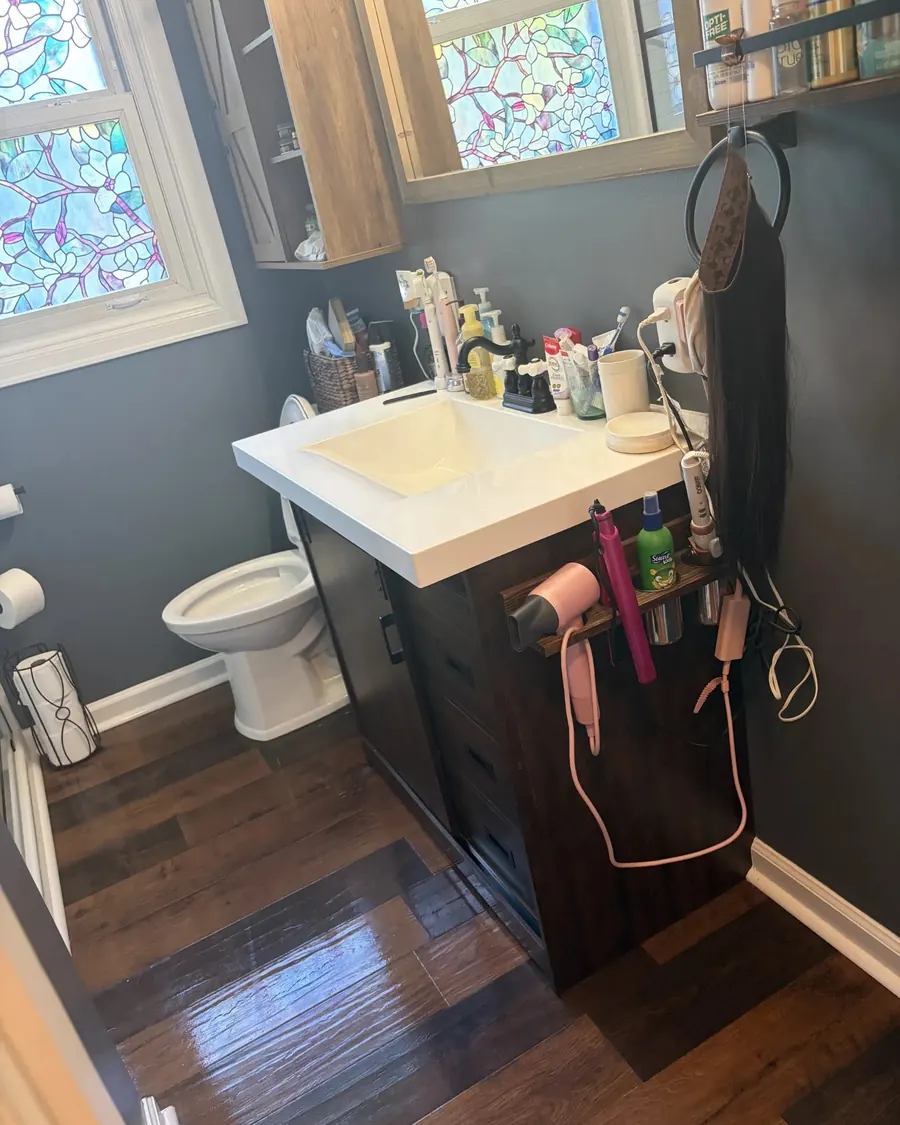 Before: a bathroom vanity crowded with bottles, tools and cords